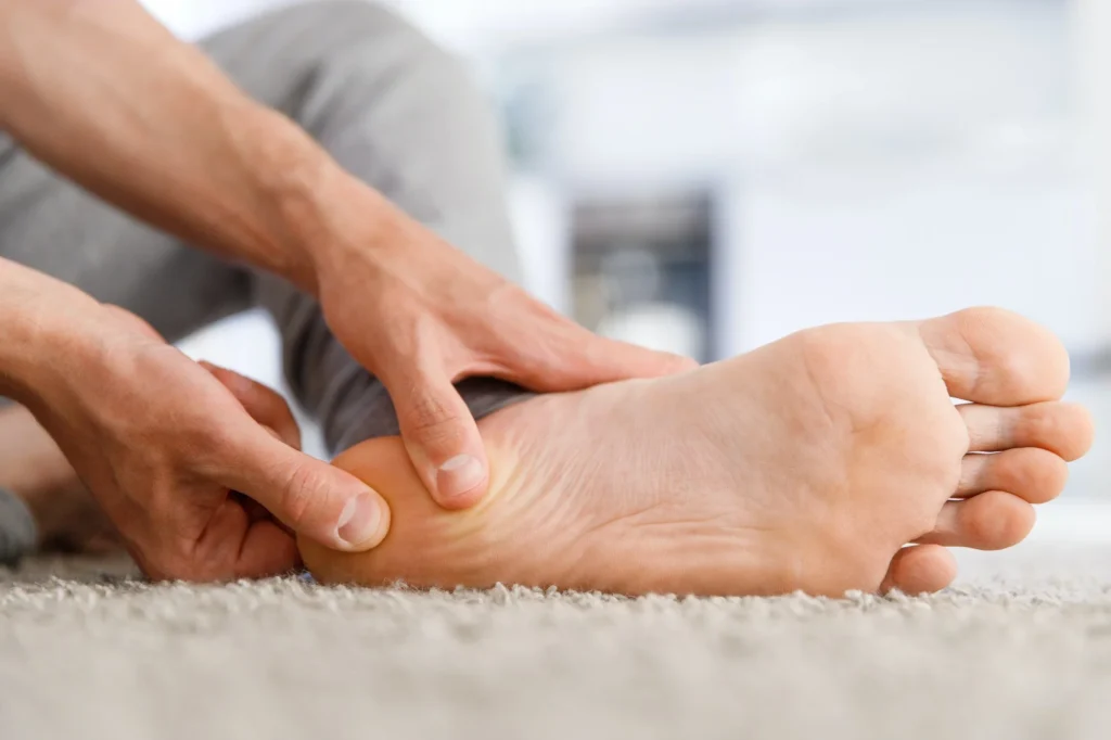Person using both hands to massage the sole and heel of their own foot
