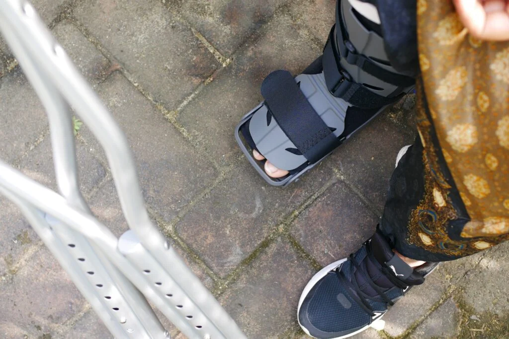 Person wearing a walking boot and using crutches