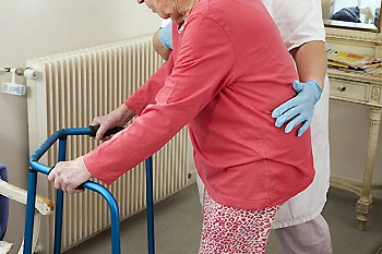 Healthcare professional assisting an older adult using a walker